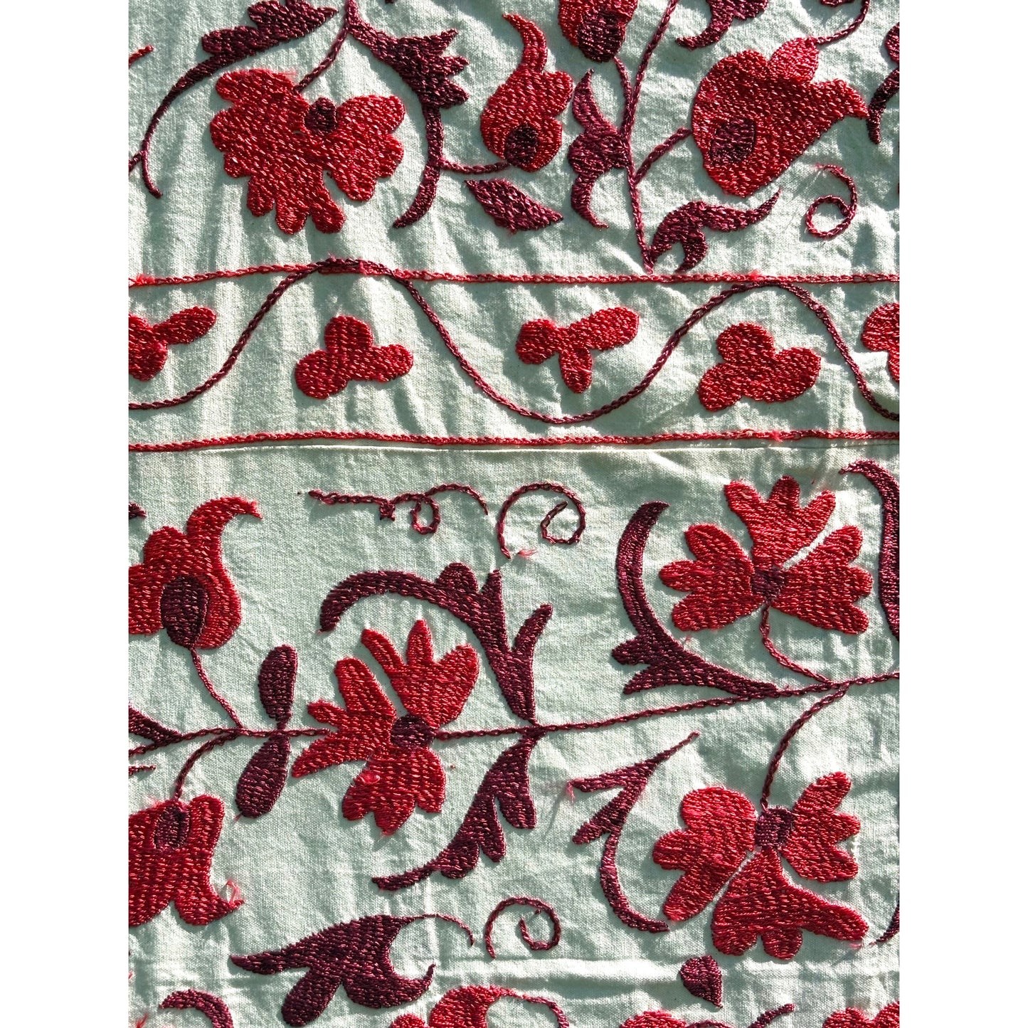 Close-up of cherry red floral embroidery on a light fabric background
