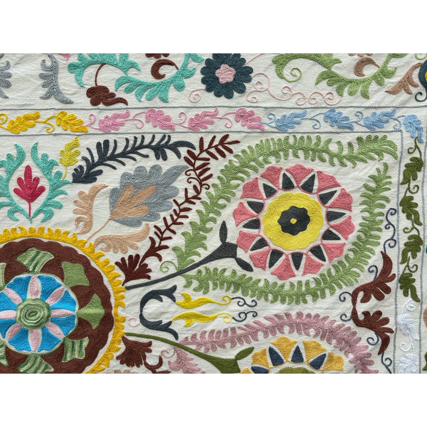 Colorful embroidered fabric with floral and leaf patterns on a white background