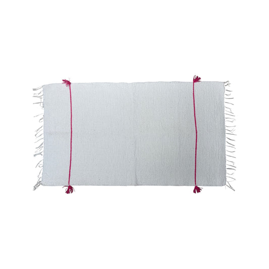 a white bath mat with red stitching on a white background.