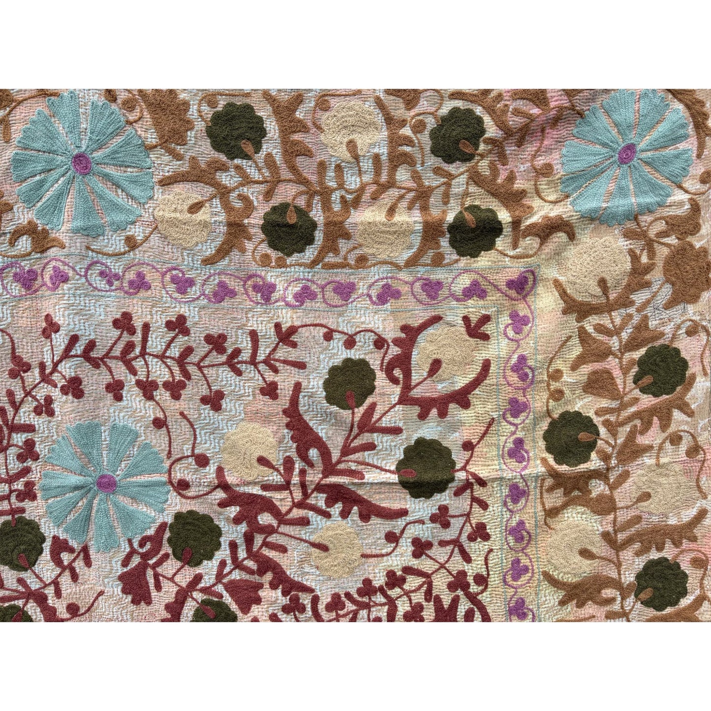 Close-up of a embroidered fabric with floral and leaf patterns.