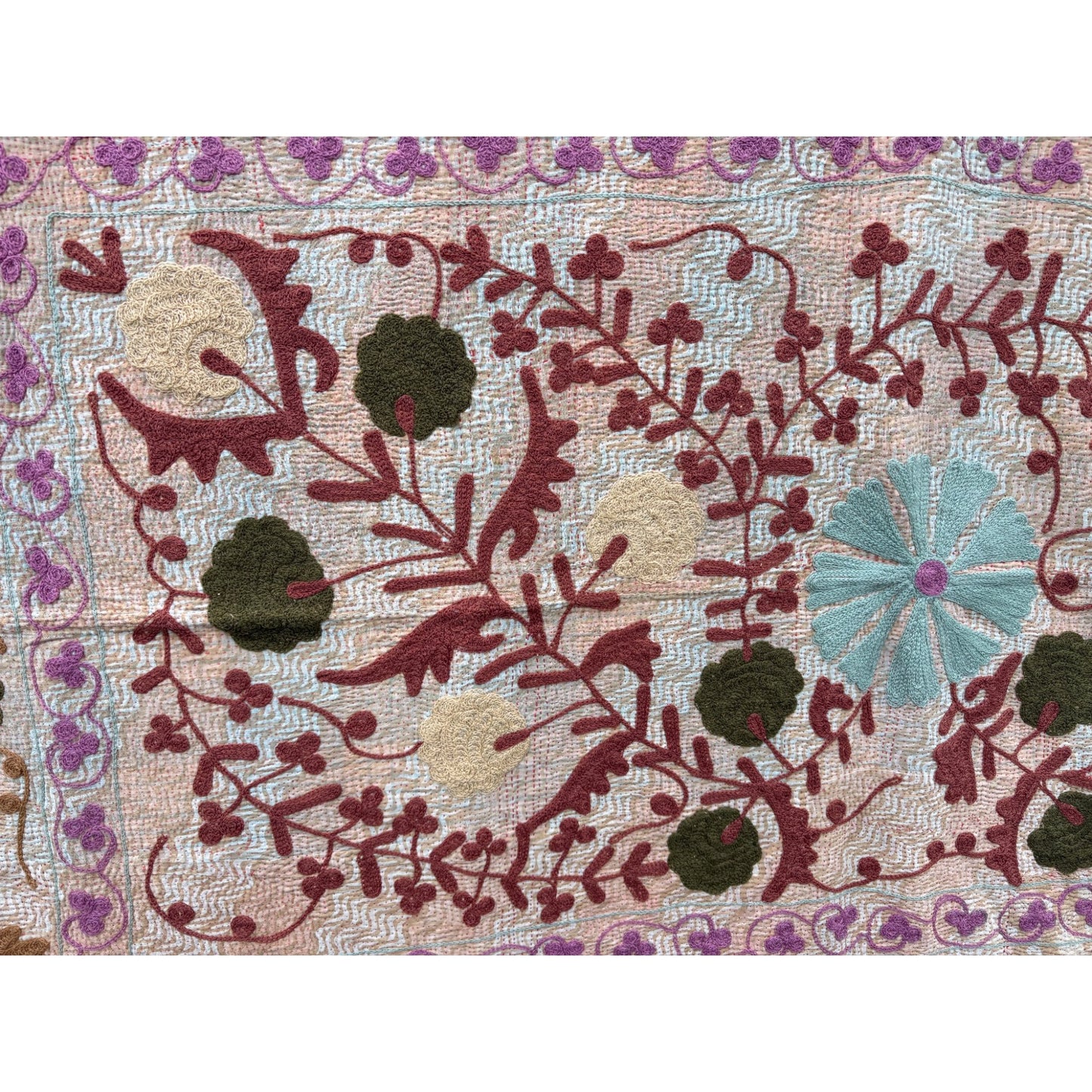 Decorative fabric with floral and leaf patterns in red, green, and blue on a beige background.