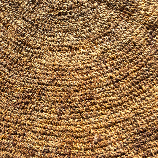 A close-up texture shot of a brown and tan loop-pile carpet or rug, showing the detailed pile height and color variation.