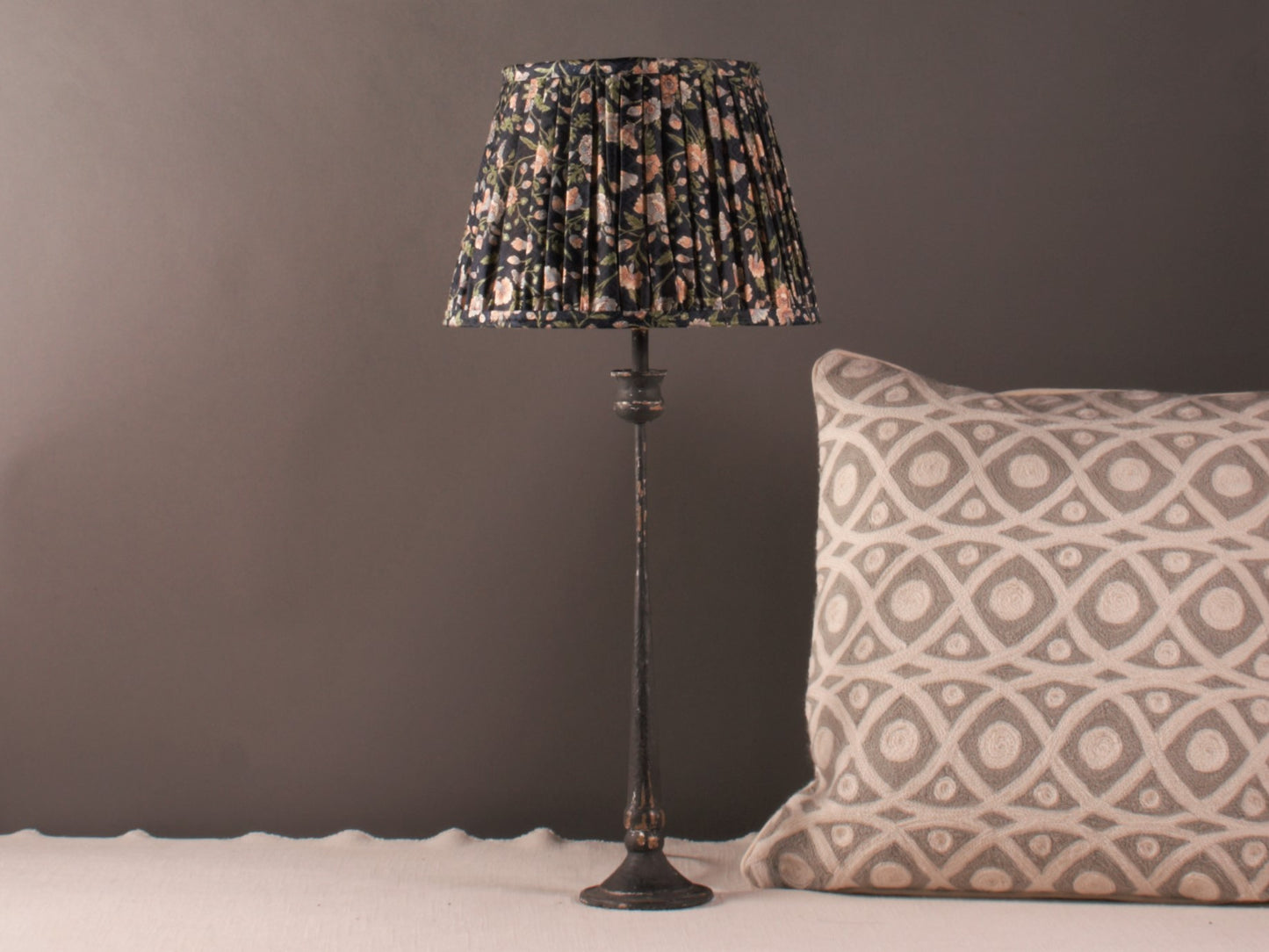 Navy with Floral Silk Lampshade shown on a candle stick lamp base, syled with a grey samarkand pillow