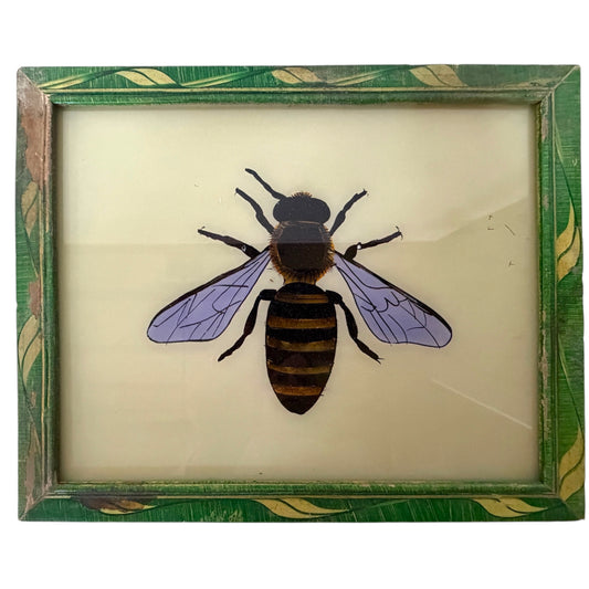 A framed vintage insect specimen featuring a painted bee on a cream-colored backing, surrounded by a distressed green and gold leaf-patterned frame.