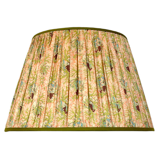 A gathered silk lampshade featuring a vintage coral and seaweed botanical pattern with green leaves, peach and pink flowers finished with olive green trim at the top and bottom.