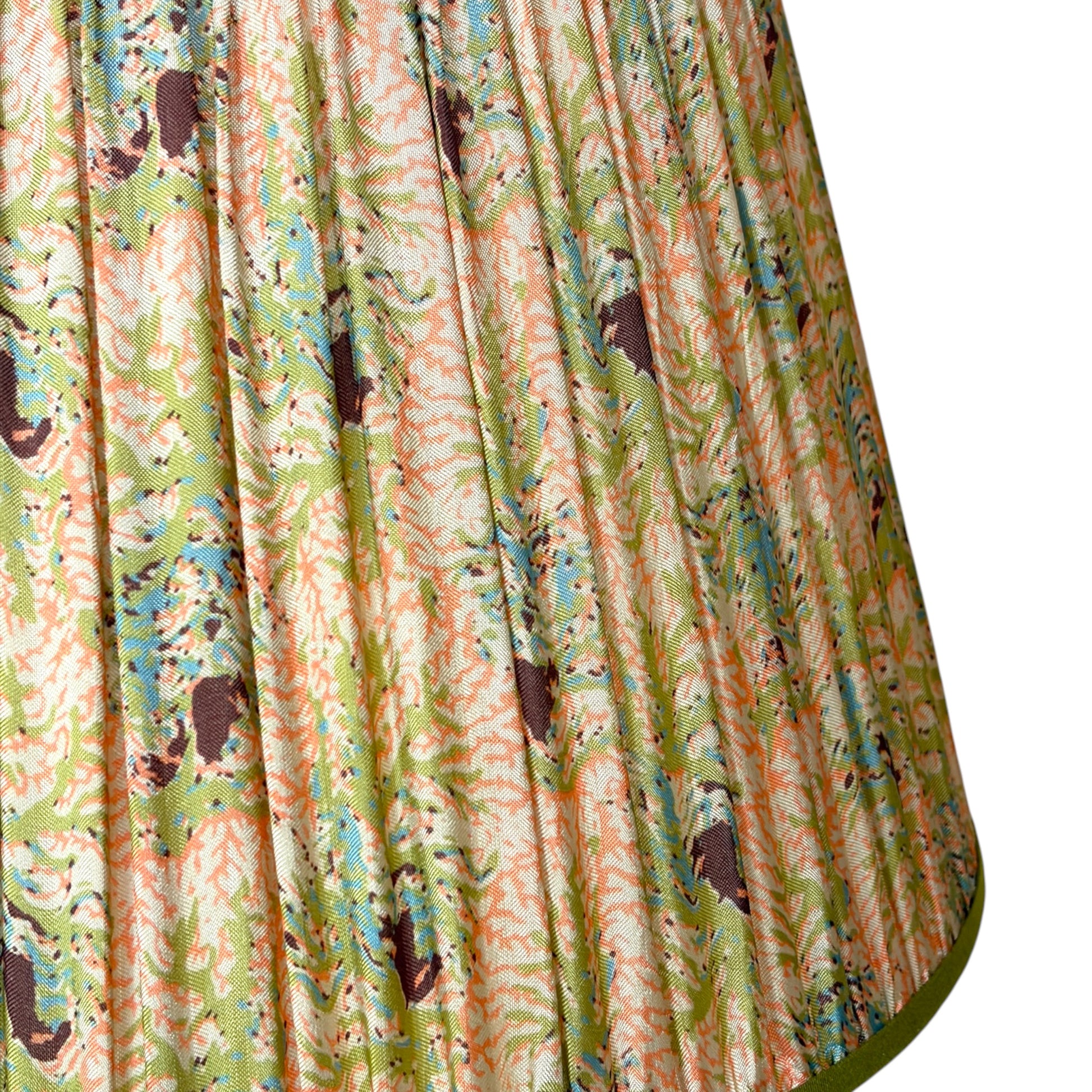 A close-up of a gathered silk lampshade featuring a vintage coral and seaweed botanical pattern with green leaves, peach and pink flowers finished with olive green trim at the top bottom.