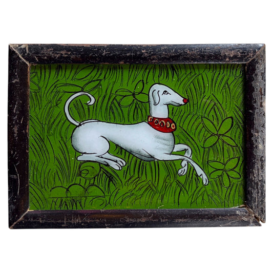 A framed art print depicting a white Italian Greyhound dog wearing a red collar, running through a green grassy field with stylized flowers. The piece is housed in a distressed, dark brown wooden frame.