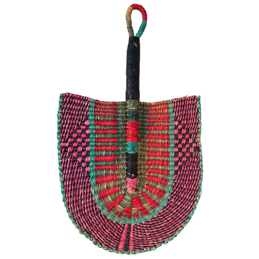 One side of a handwoven Ghanaian Bolga fan in pink, green and black raffia with a leather-wrapped handle, shield-shaped weave, against a white background, facing downwards from handle