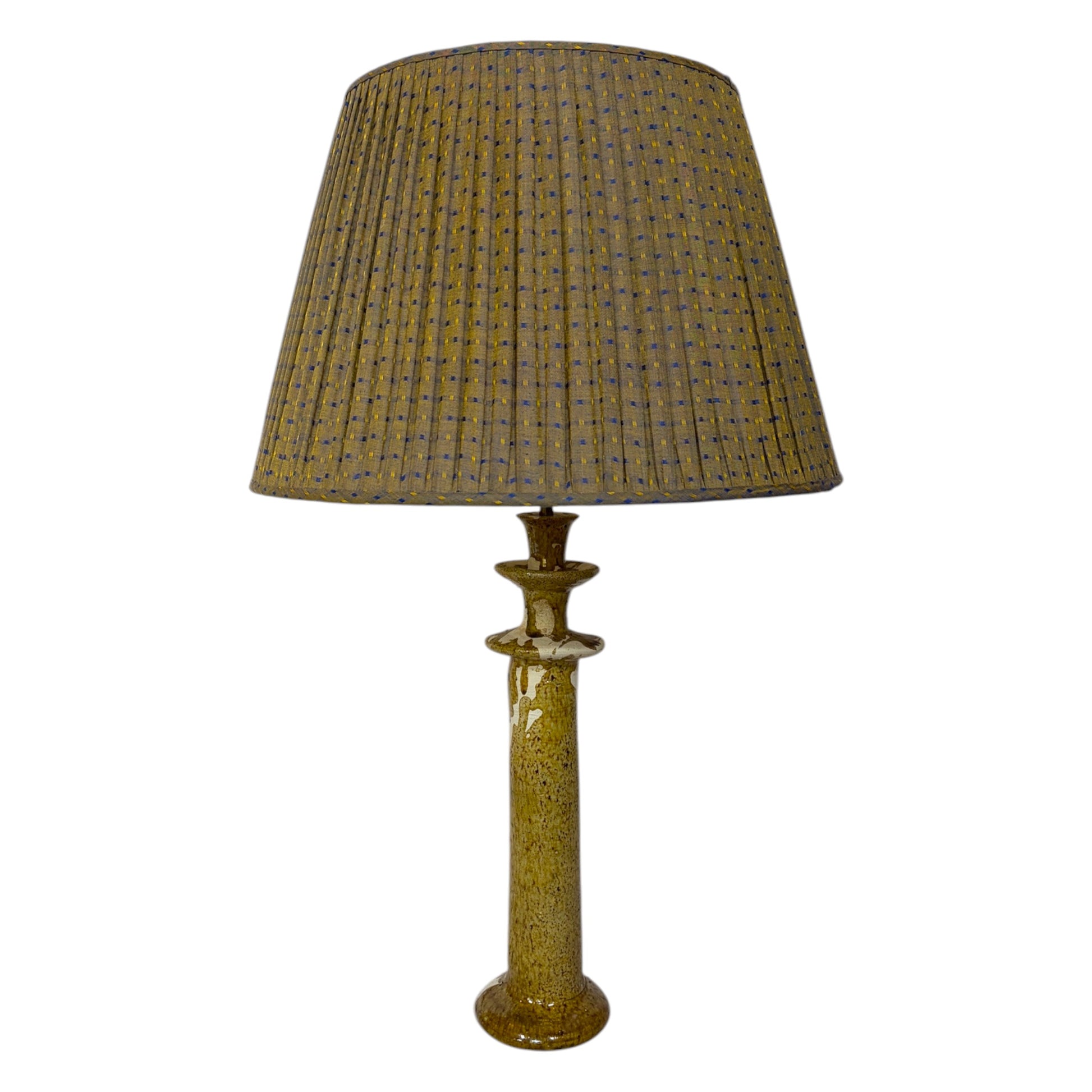A Tamegroute table lamp, textured, speckled column base in a warm ochre and cream colour, isolated on a white background.