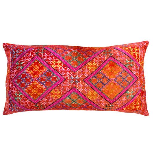 A rectangular Swat Valley Wedding Cushion featuring a vibrant, multicolored geometric pattern with prominent pink, orange, red, and blue embroidery. 