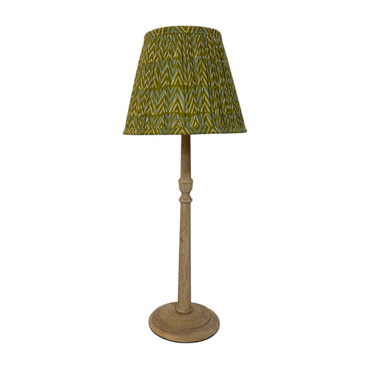 A mango wood table lamp with a lampshade featuring a green and yellow chevron pattern, supported by a rustic light brown wooden stem and round base, set against a plain white background.