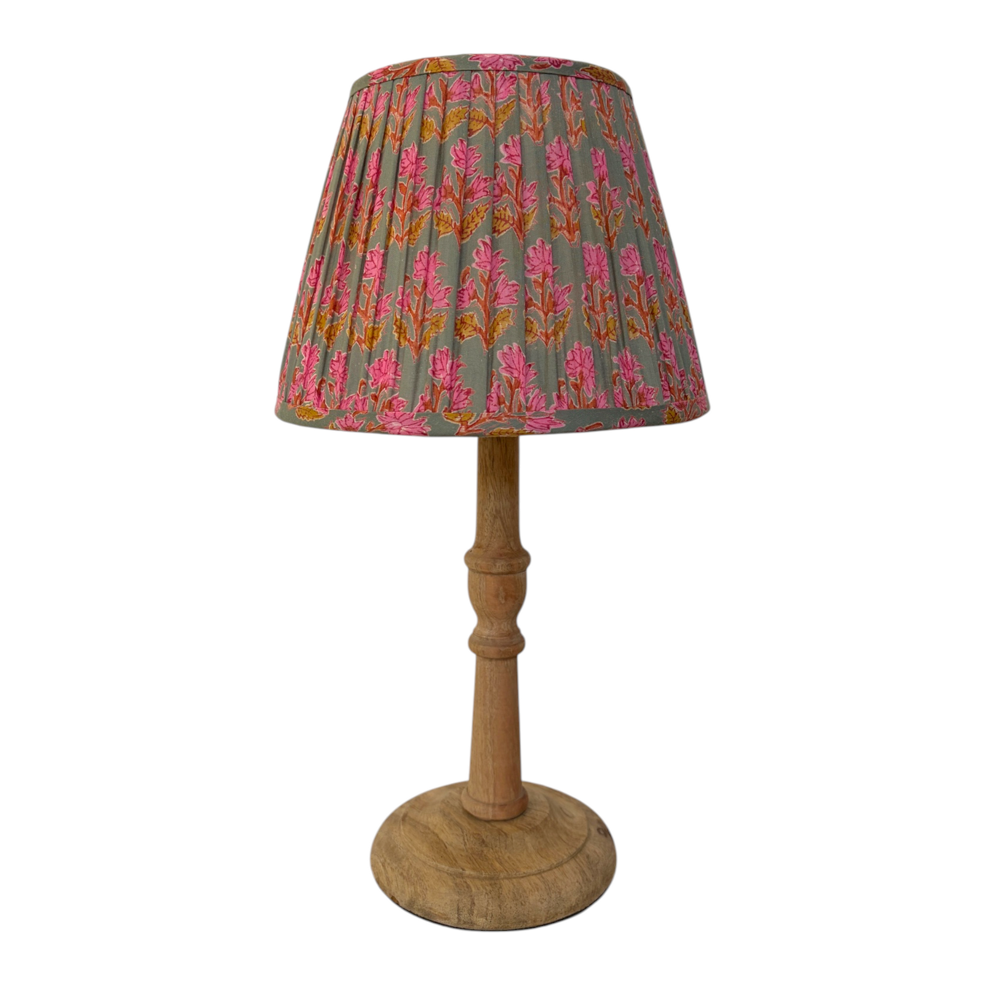 A small table lamp with a pleated fabric shade featuring a pink and orange floral pattern on a muted sage green background, supported by a natural wood pedestal base with a round wooden footplate, set against a plain white background.