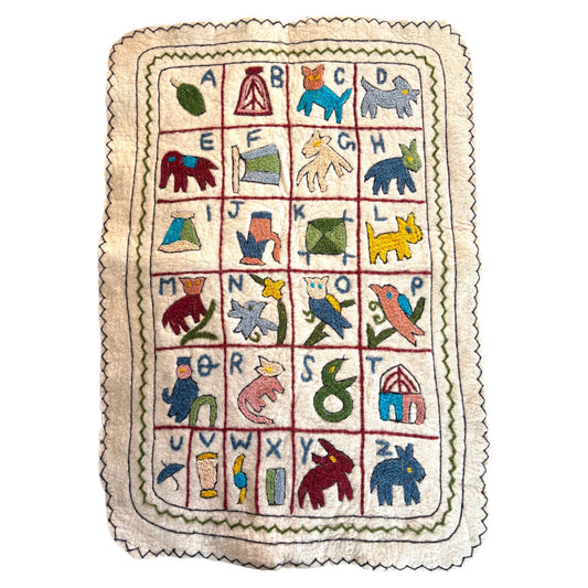 Alphabet wall hanging, showing a Namda technique. Cream wool with colourful embroidery on a white background. 