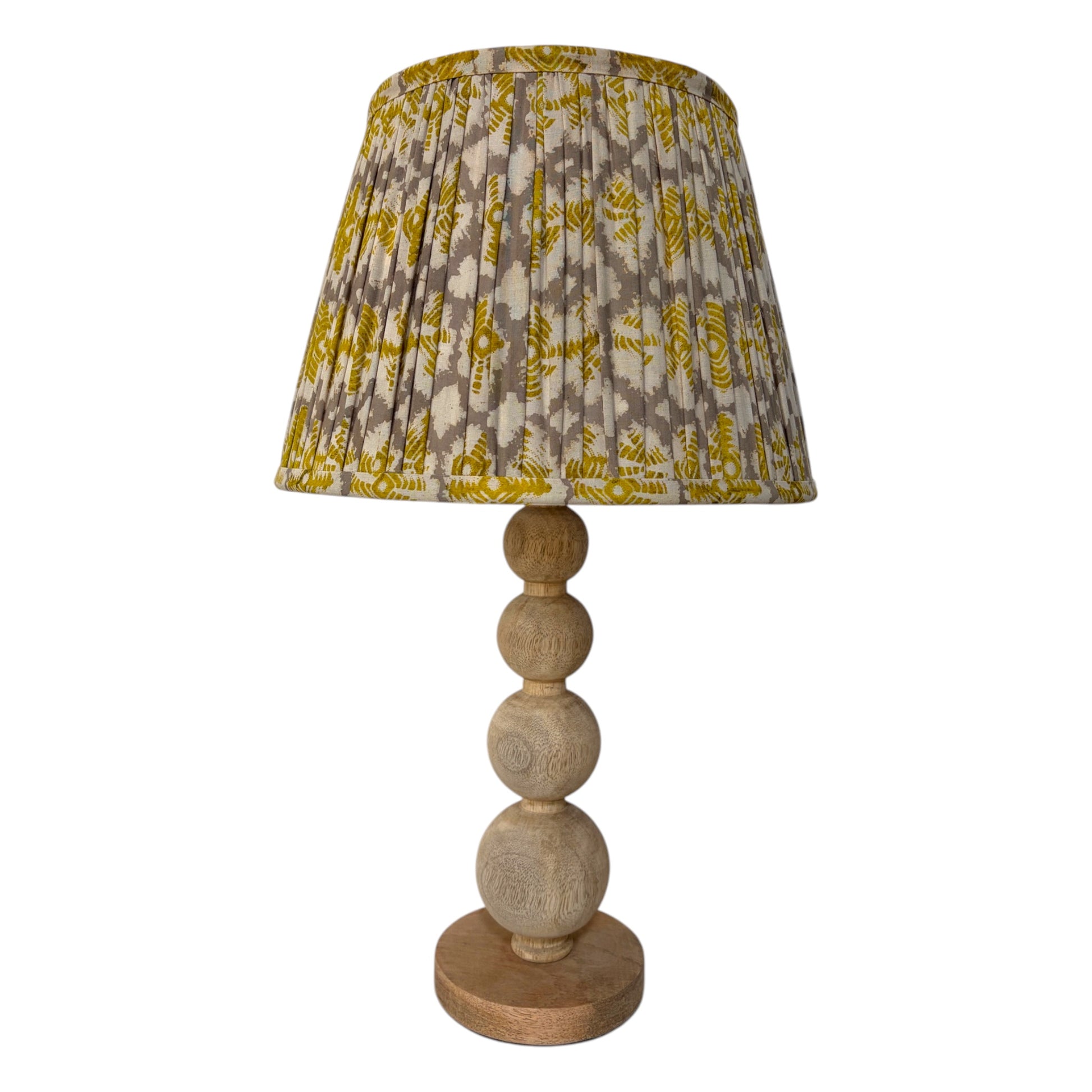 A table lamp with a pleated fabric shade featuring a yellow and gray yoyo pattern, supported by a natural wood ball-spindle base on a white background.