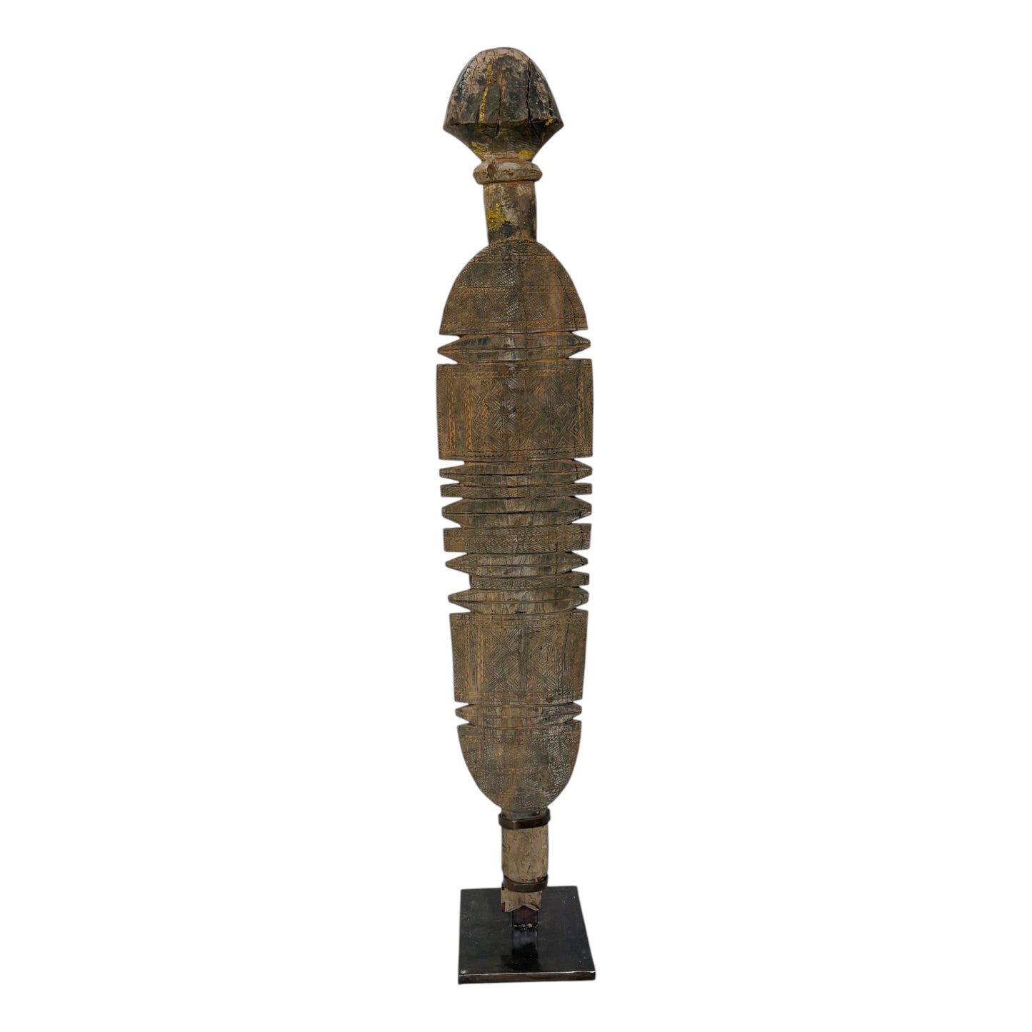 A tall, narrow carved wooden decorative sculpture with a weathered brown and black finish, standing on a small black base against a plain white background.