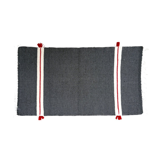 A rectangular dark gray bath mat featuring two vertical white stripes with red borders and red tassels at the ends, shown flat against a white background.