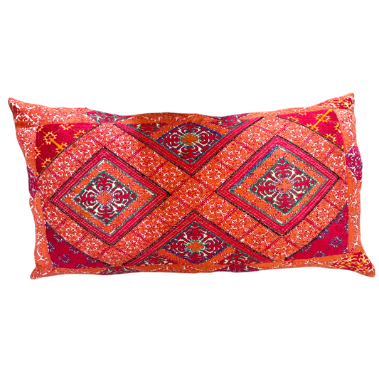 The front view of a rectangular Swat Valley Wedding Cushion featuring a vibrant, multicoloured patchwork design with diamond patterns in red, orange, blue, and green.