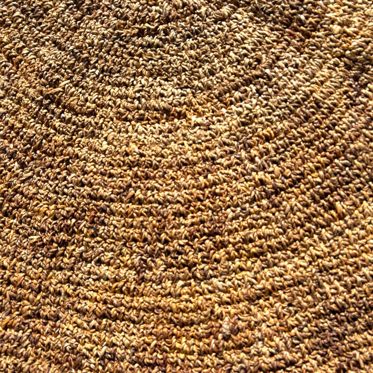 A close-up texture shot of a brown and tan loop-pile carpet or rug, showing the detailed pile height and color variation.