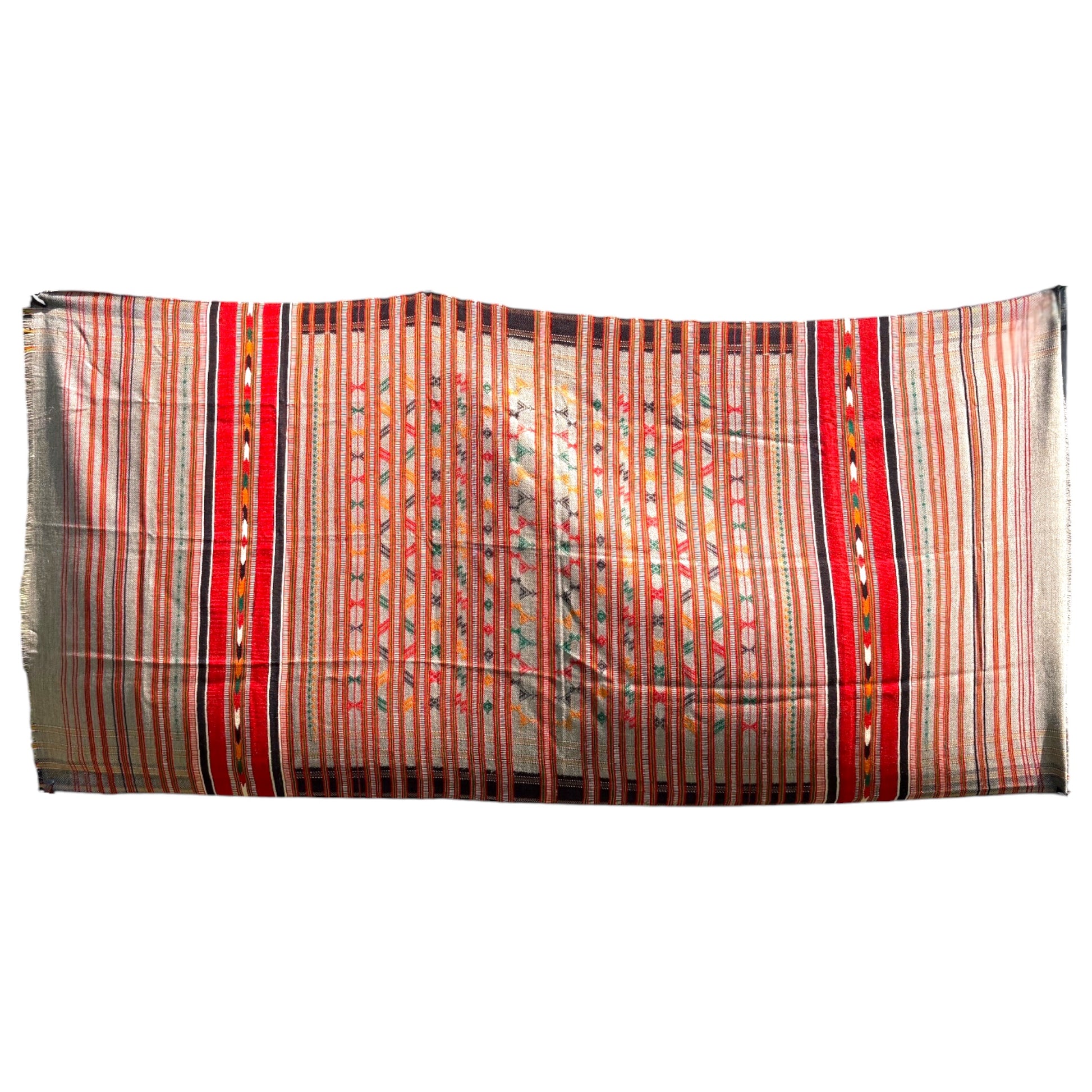 A rectangular woven textile with vertical striped patterns in red, orange, beige, and black, featuring geometric motifs and fringed edges, shown against a plain white background.