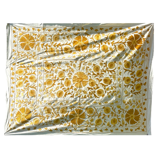 A Suzani featuring an intricate golden-yellow floral and vine pattern. 