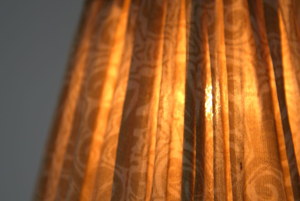 Butter paisley silk lampshade extreme close-up with light bulb on