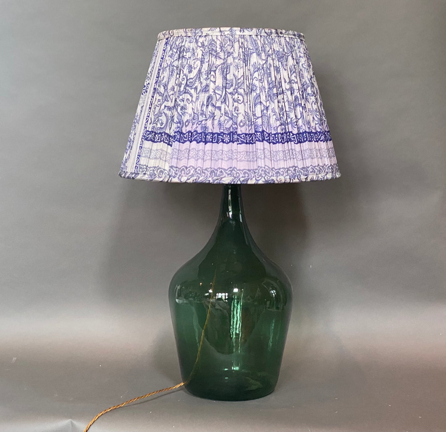 Royal Blue Paisley silk lampshade displayed on a green bottle lamp base on a grey background