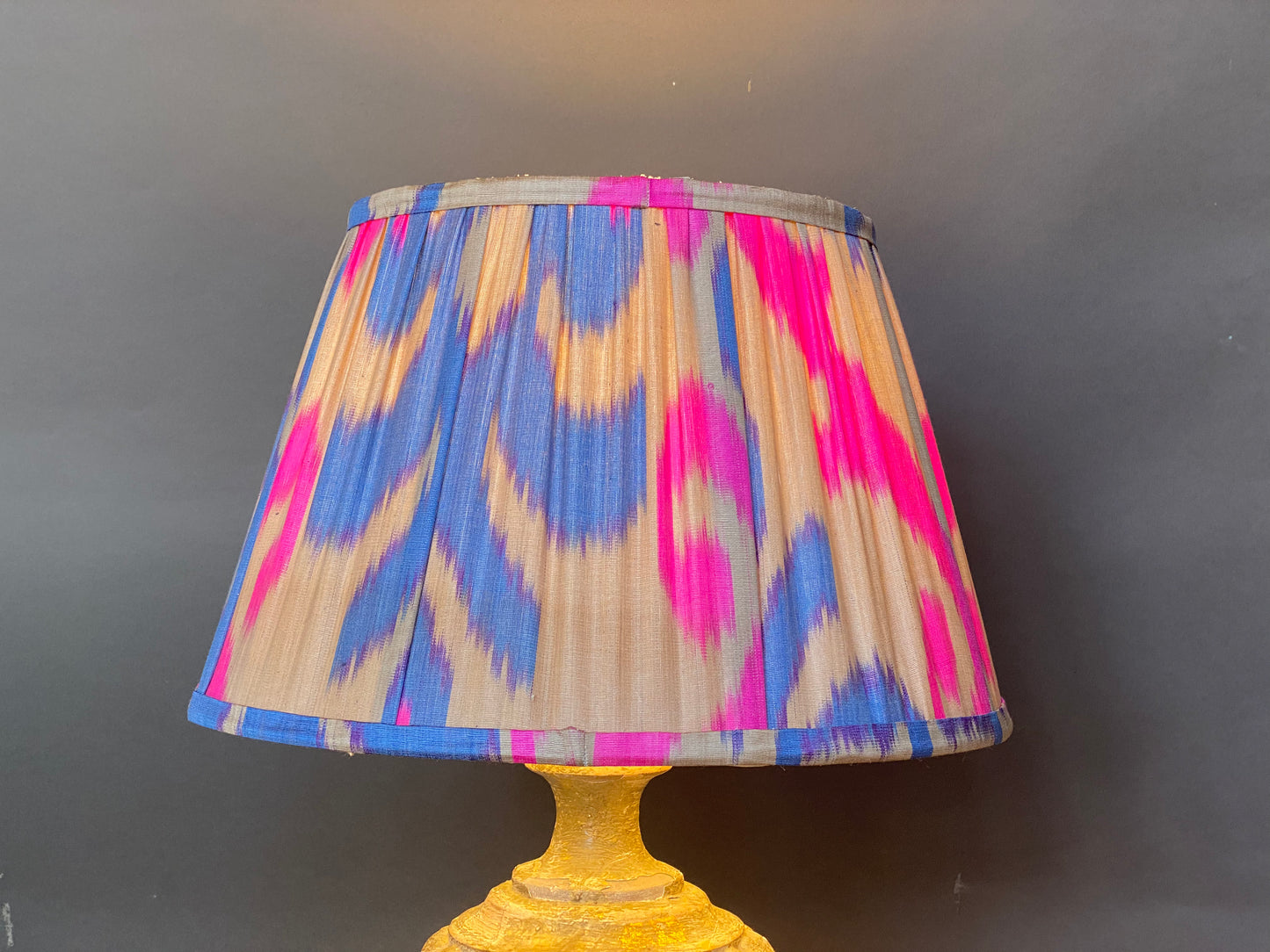 Bright pink and blue ikat silk lampshade with light bulb on